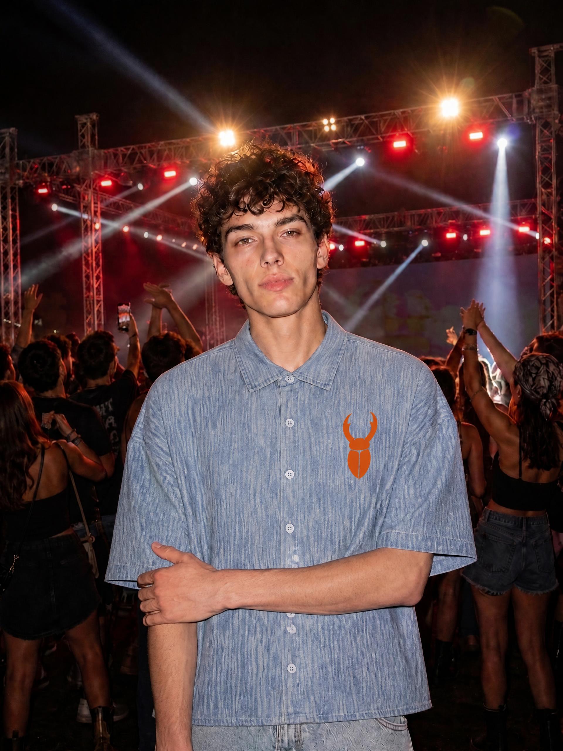 Model wearing a Staghorn vintage wash denim shirt with an orange beetle logo.